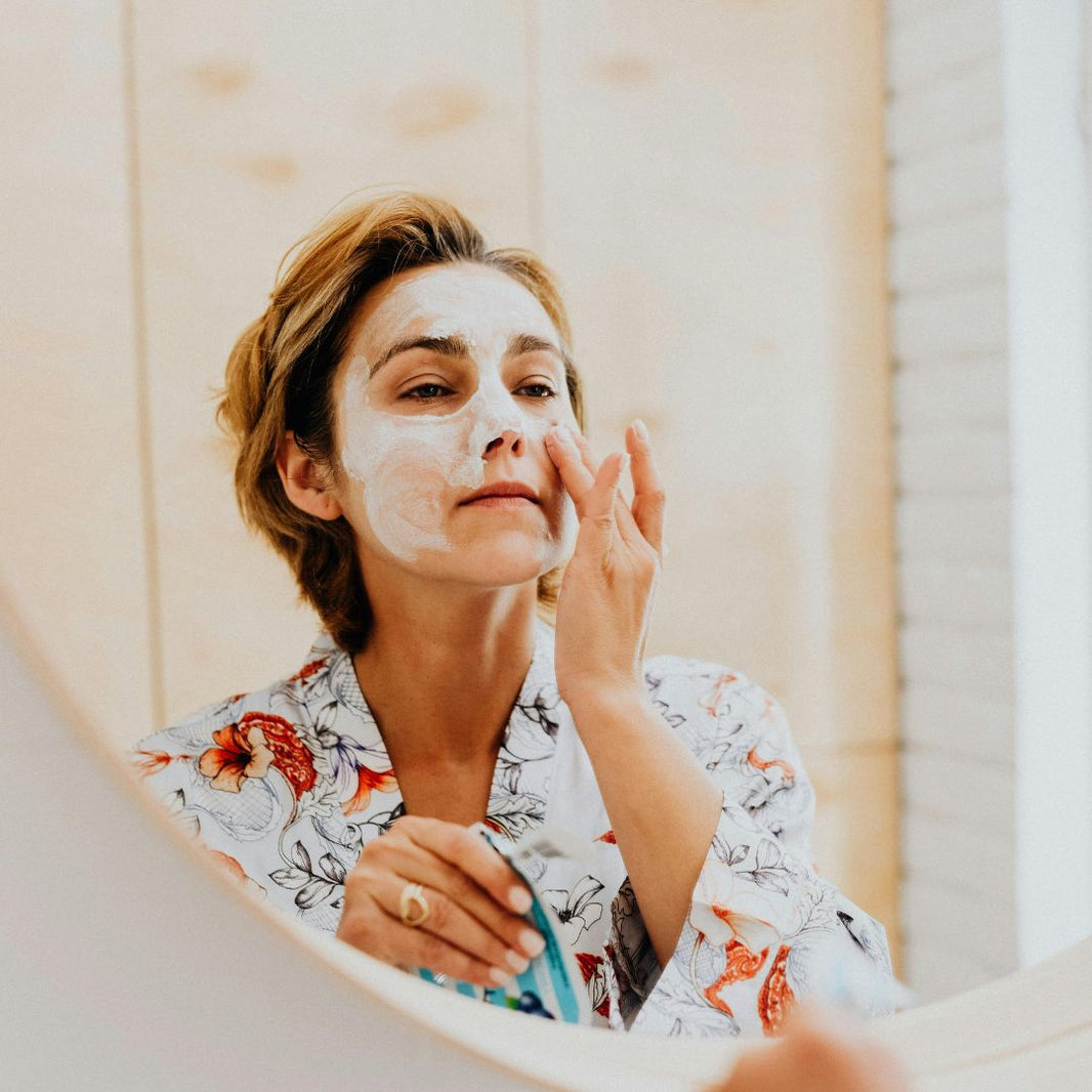 woman applying facial cleanser looking in mirror
