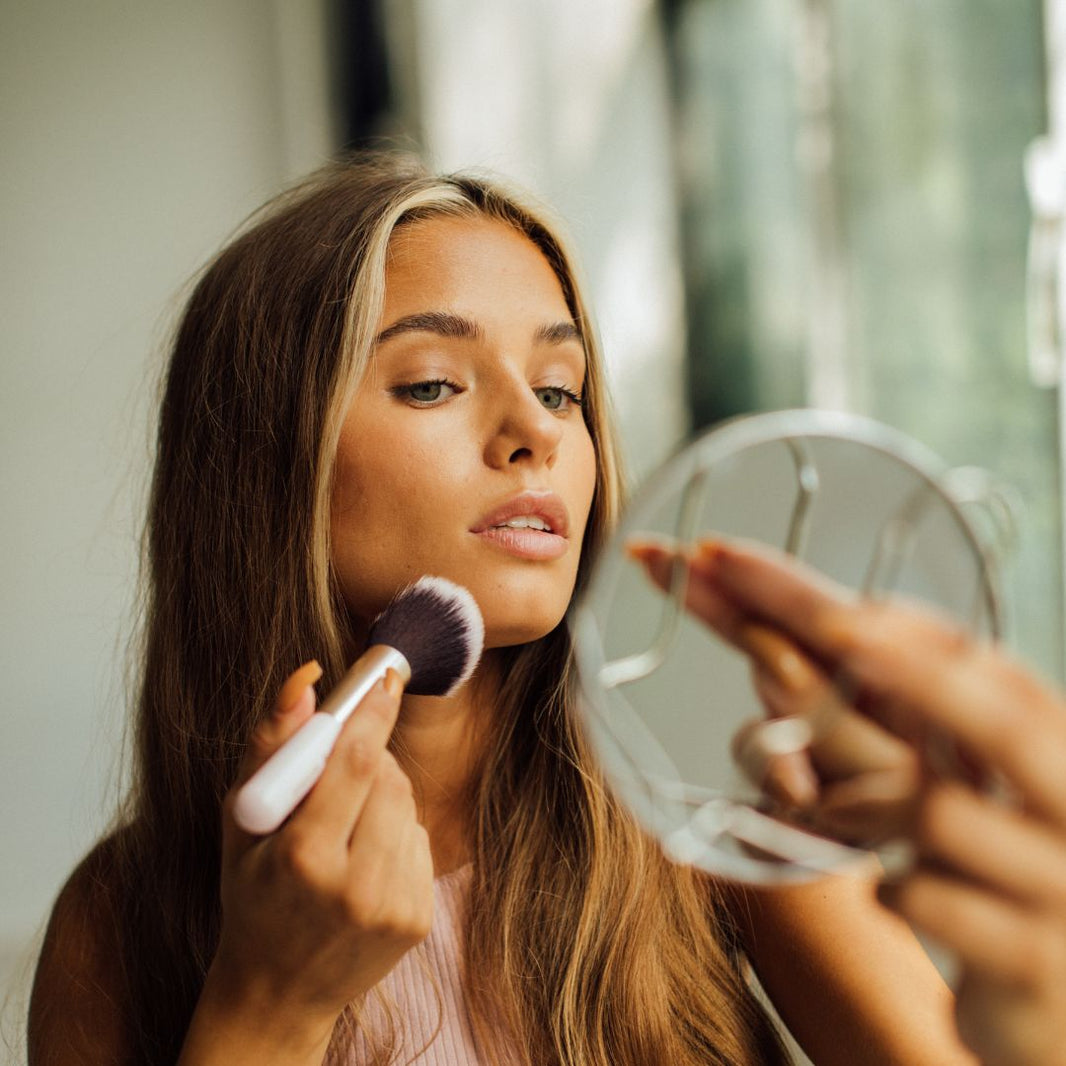 woman applying makeup with mirror